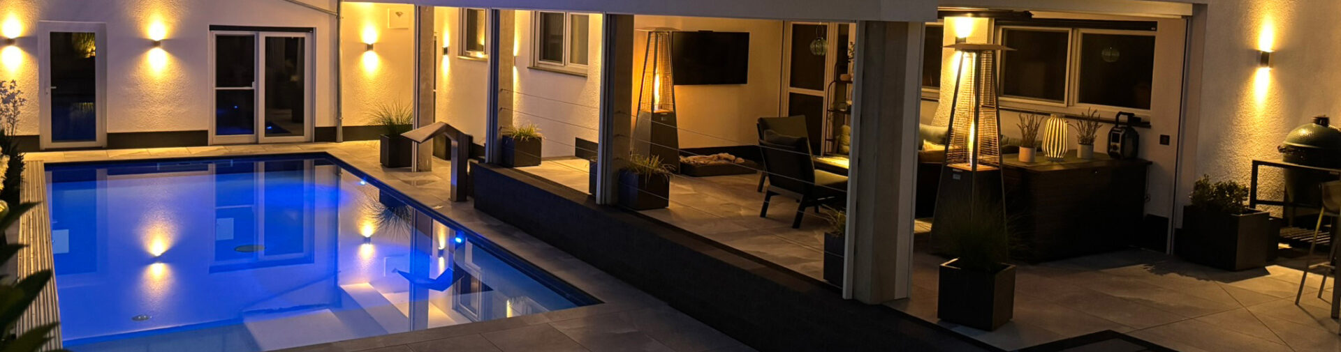 Beleuchteter Pool an moderner Terrasse bei Nacht